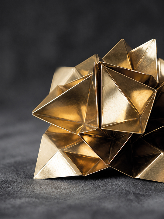 Bespoke Sculpture Morocco featuring a gold geometric sculpture with faceted metallic surfaces in a refined studio close-up.